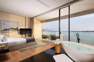 1 dormitorio con bañera y 1 cama con vistas en Floral Luxury Wuhu Lake Art Hotel, en Wuhu