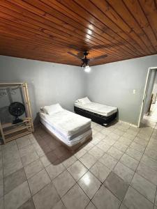 two beds in a room with a wooden ceiling at Casa em Juquehy 200m da praia in São Sebastião