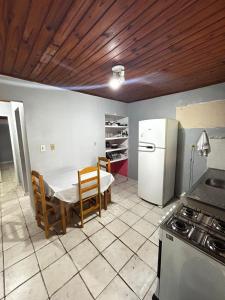 a kitchen with a table and a white refrigerator at Casa em Juquehy 200m da praia in São Sebastião +7 photos