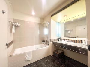 ein Badezimmer mit Badewanne, Waschbecken und Spiegel in der Unterkunft Charming Studio Apartment in Auckland Central in Auckland + 13 Fotos