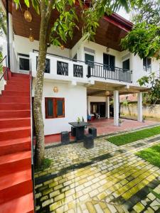 a white house with a tree and a red staircase at Double G Motel in Weligama