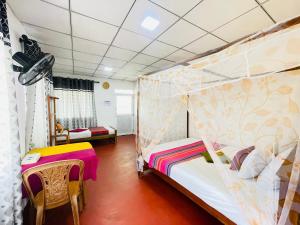a bedroom with two beds and a table and chairs at Double G Motel in Weligama