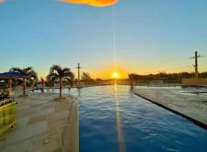 a swimming pool with a sunset in the background at Resort Praia Grande in Arraial do Cabo