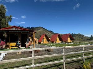 a row of wooden cabins with a fence in front at Sigchos Lodge in Sigchos