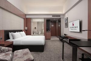 a hotel room with a bed and a living room at Vanburgh Hotel Guangzhou in Guangzhou