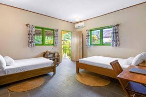 a room with two beds and a table and windows at Amy's Place Sumatra in Krui