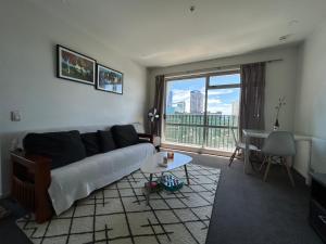 Una sala de estar con un sofá y una mesa y una ventana. en Adjacent to the Sky Tower, with a super large space, en Auckland