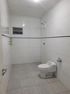 a bathroom with a toilet in a white tiled room at RR 2 Pousada e Restaurante in Manaus