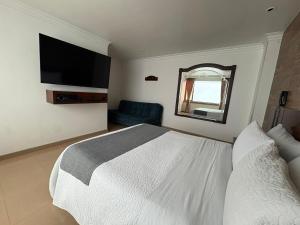 Un dormitorio con una cama blanca y un televisor de pantalla plana. en Lavid Hotel Palacio Real, en Bogotá 79 fotos más