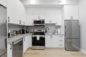 une cuisine avec des armoires blanches et des appareils en acier inoxydable dans l'établissement Stylish 3BR CN Tower Views & Patio Mini Putt, à Toronto