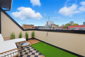 un petit patio avec une pelouse verte sur un balcon dans l'établissement Stylish 3BR CN Tower Views & Patio Mini Putt, à Toronto 41 autres photos