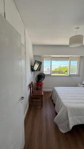 a white bedroom with a bed and a window at La gracie in San Bernardo