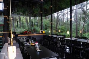 a restaurant with black tables and chairs and large windows at Shuitiao Boli Hotel (Yangshuo Shili Gallery Yulonghe Branch) in Gaotian