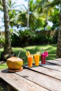a wooden table with three drinks and a bowl of food at Amy's Place Sumatra in Krui
