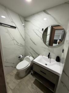 ein Badezimmer mit Toilette, Waschbecken und Spiegel in der Unterkunft Apartamento Aluke in Cali