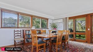 a dining room with a table and chairs and windows at Art House - 4 Bedroom in Barragga Bay +7 photos
