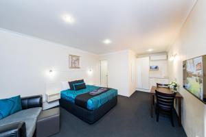 ein Schlafzimmer mit einem Bett, einer Couch und einem Tisch in der Unterkunft Wondai Colonial Motel & Ivory's Restaurant in Wondai + 37 Fotos