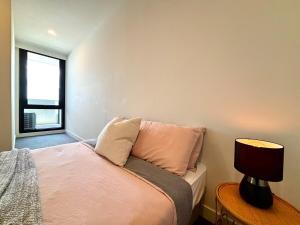 北克莱顿M-City Monash Spacious Skyline Escape & Hospital的卧室里有一张床和一张带灯的桌子