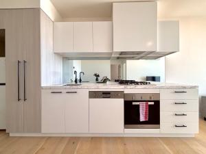 北克莱顿M-City Monash Spacious Skyline Escape & Hospital的厨房配有白色橱柜和炉灶烤箱