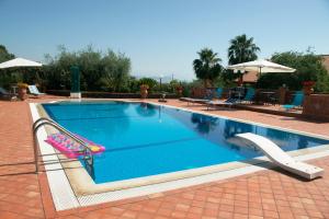 a swimming pool with two chairs and an umbrella at Villa del Sole in Zafferana Etnea