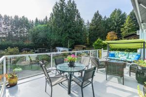 Un patio con una mesa y sillas en un balcón. en Bayview Bed and Breakfast, en Mill Bay