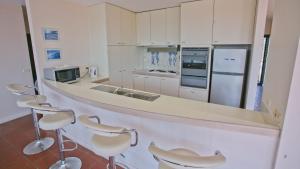 伯马吉Beach Pad Unit1, 2 Wallaga Street, Bermagui的厨房配有带凳子和电器的柜台