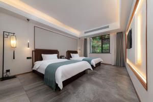 Un dormitorio con dos camas y un televisor y una ventana. en Serene Peaks Courtyard-Free pick-up-Free Laundry, en Fenghuang 33 fotos más