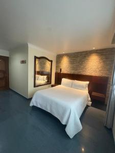 a bedroom with a large white bed and a mirror at Lavid Hotel Palacio Real in Bogotá