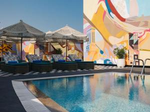 a swimming pool with chairs and umbrellas next to a building at Pullman Dubai Jumeirah Lakes Towers in Dubai