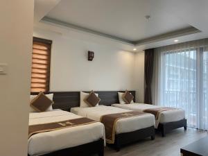 a hotel room with three beds in a room at Helen Halong Hotel in Ha Long