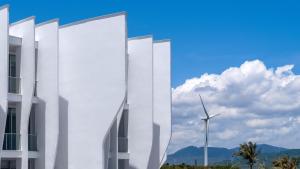 a white building with a wind turbine in the background at Orient Luxury Hotel Kenting in Hengchun South Gate