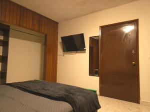 Un dormitorio con una cama y un televisor de pantalla plana. en OLYMPIA SUITES sleep local, en Saltillo