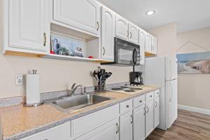 a kitchen with white cabinets and a sink and a refrigerator at Torch Lake Vista A Ga Ming Golf Retreat 741 Unit 9B in Creswell