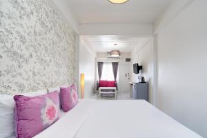 a bedroom with a white bed with pink pillows at Take a Rest Donmueang in Ban Don Muang