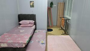 a small room with two beds and a chair at Warisan Nyonya Cabin Homestay Alor Gajah in Kampong Jelatang