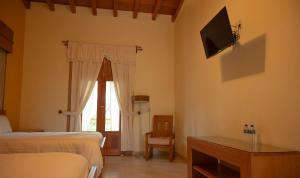 a bedroom with two beds and a television on the wall at Hotel & Spa Quinta Sauz in Tacámbaro de Codallos