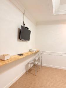 ein Raum mit einem Tisch und einem Fernseher an der Wand in der Unterkunft Pophouse in Phetchaburi