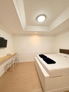 a white room with a bed and a desk at Pophouse in Phetchaburi