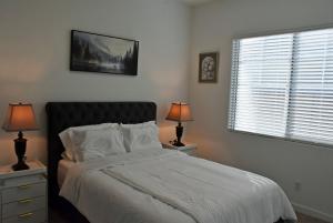 a bedroom with a bed with white sheets and two lamps at BnB Vacation Home in Queen Creek