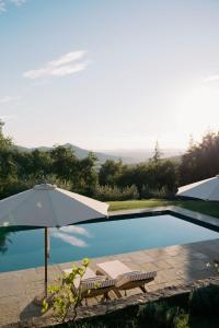 an umbrella and a bench next to a swimming pool at Villa Montanare - romantic escape Tuscany in Cortona
