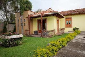 a small yellow house with a porch and a yard at Hotel & Spa Quinta Sauz in Tacámbaro de Codallos