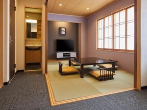 Una sala de estar con una mesa y un televisor. en Hotel Lorelei, en Sasebo