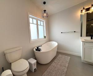 a bathroom with a tub and a toilet and a sink at Cozy Heaven in Saskatoon +40 photos