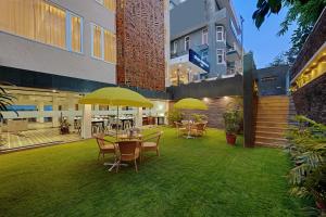 古尔冈Ahuja Residency GCR的庭院配有桌椅和黄色遮阳伞