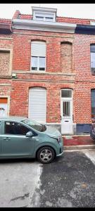 a blue car parked in front of a brick building at Maison partagée 4 chambres Saint Roch Roubaix in Roubaix