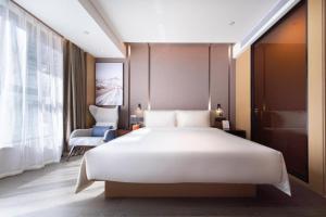 a bedroom with a large white bed and a chair at Atour Hotel Shenzhen Nanshan Shili Metro Station in Shenzhen +28 photos