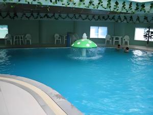 une grande piscine avec un parasol vert dedans dans l'établissement Jincheng Pacific Hotel, à Jingcheng