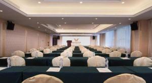 a large room with rows of chairs and a screen at Guangna Hotel in Huizhou