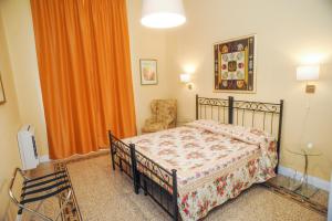 フィレンツェにあるResidenza Arrivabeneのベッドルーム1室(ベッド1台、椅子、オレンジ色のカーテン付)