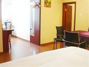 une pièce avec deux chaises, une table et un lit dans l'établissement GreenTree Inn Shanghai Songjiang Xinqiao Jiuxin Road Express Hotel, à Chunshen
